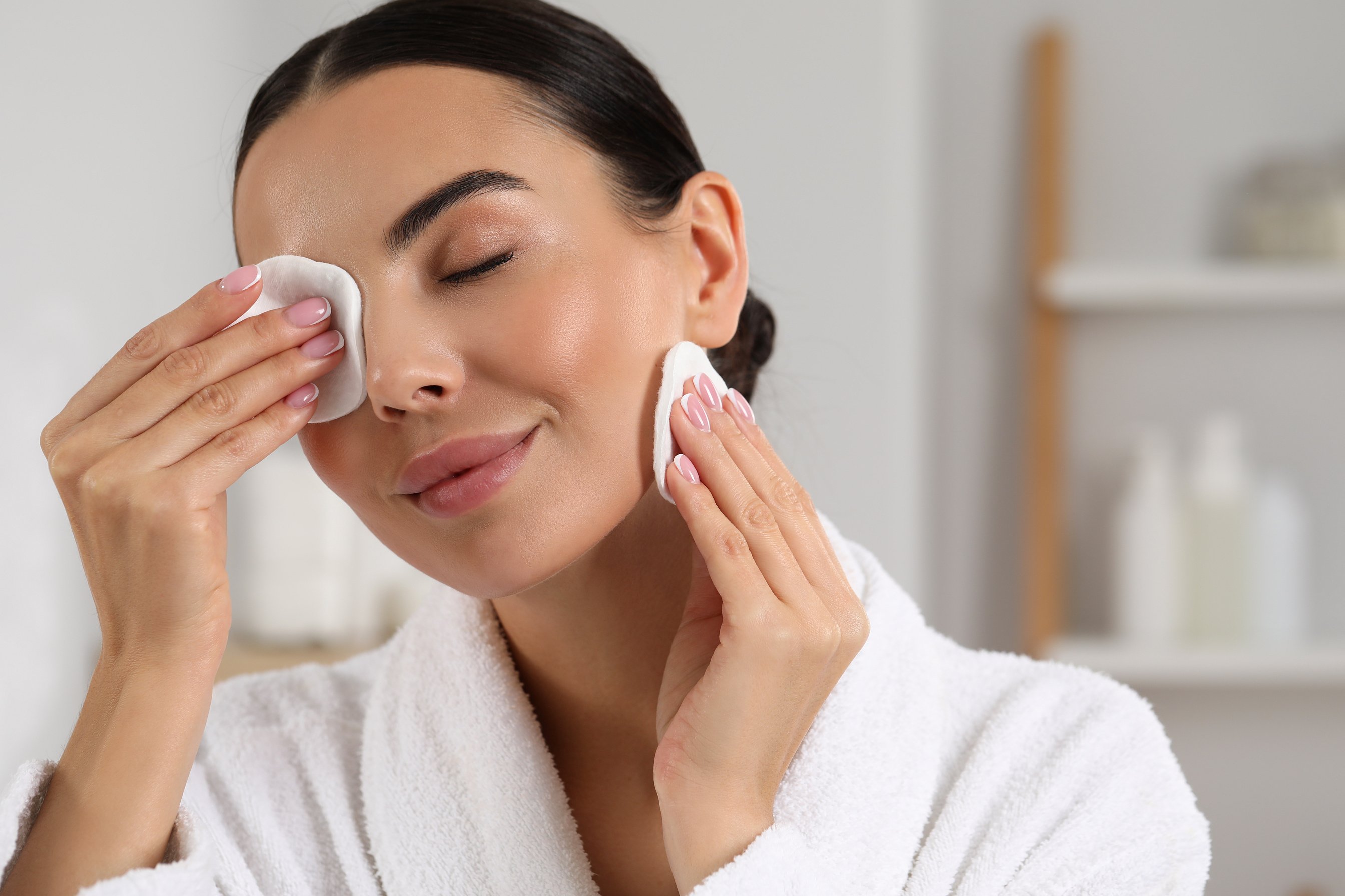 Beautiful Woman Removing Makeup with Cotton Pads Indoors