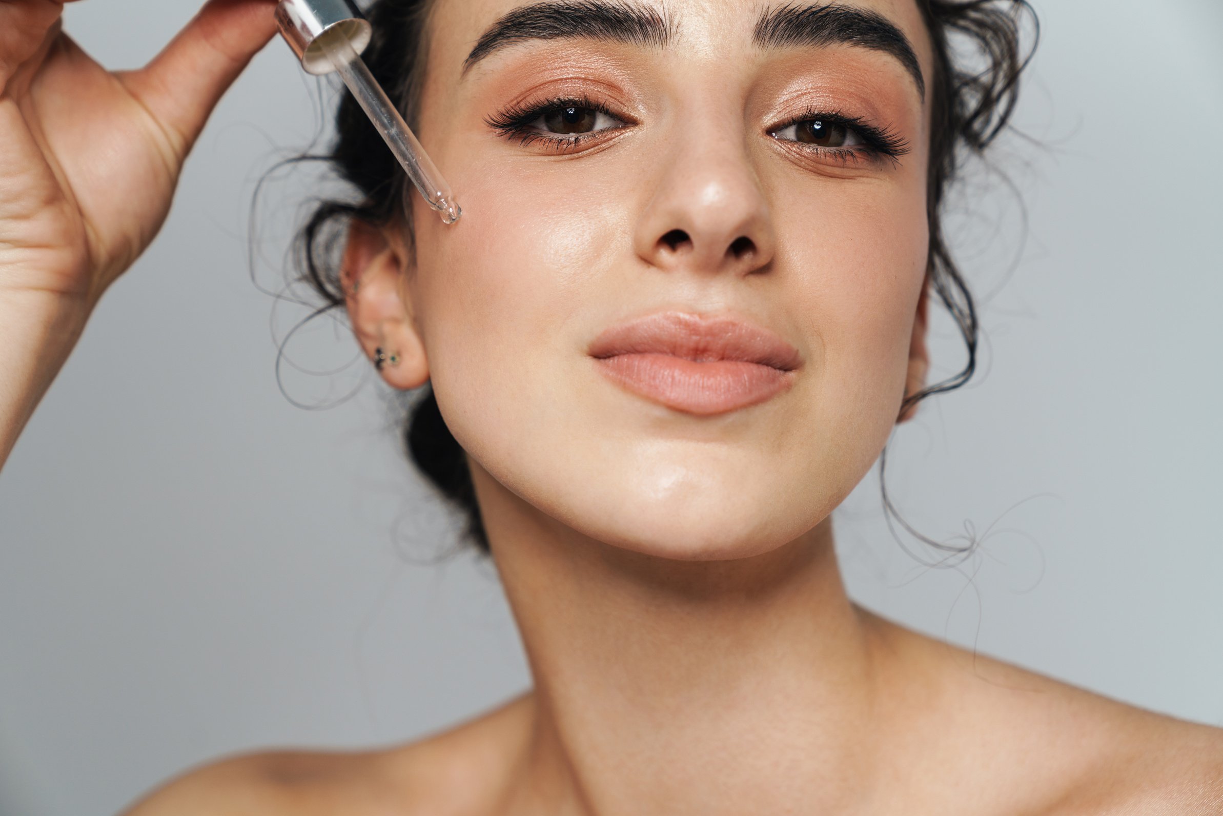 Woman with Curly Hair Applying Facial Serum